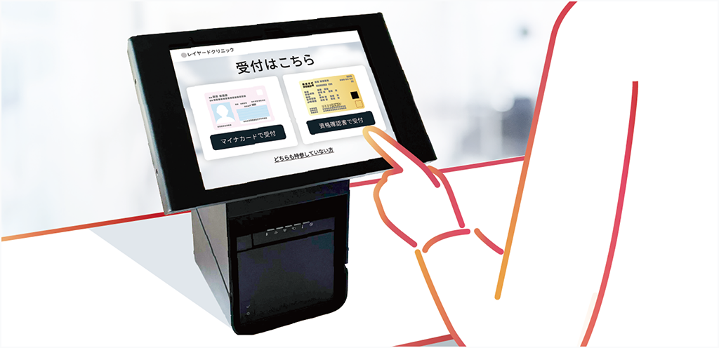 クリニックの無人受付端末で患者が受付操作を行いスタッフの業務負担を軽減する様子